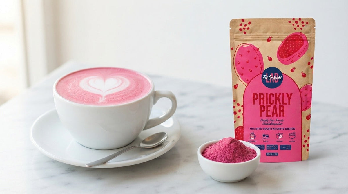 Two pink prickly pear lattes with heart-shaped latte art beside The Organic Labs Prickly Pear Powder 70g pouch