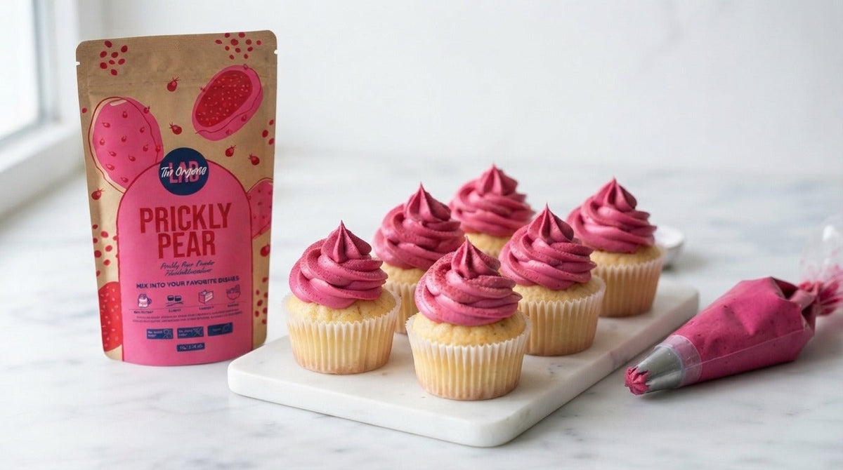 Vanilla cupcakes with pink prickly pear frosting, one cupcake cut open, alongside The Organic Labs Prickly Pear Powder